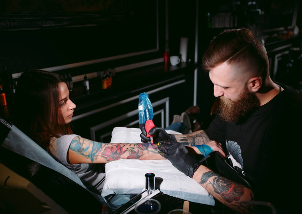 Professional tattoo artist makes a tattoo on a young girls hand. - Fotografie, Obrázek