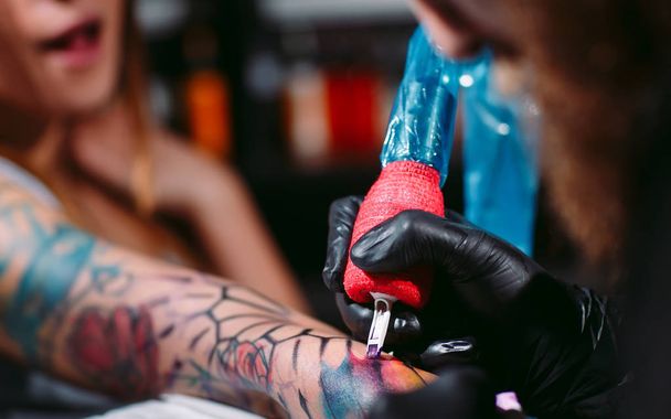 Professional tattoo artist makes a tattoo on a young girls hand. - Photo, Image