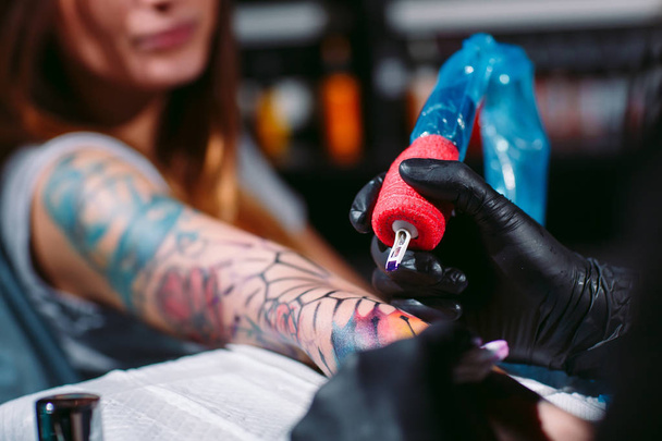 Professional tattoo artist makes a tattoo on a young girls hand. - Foto, Imagem
