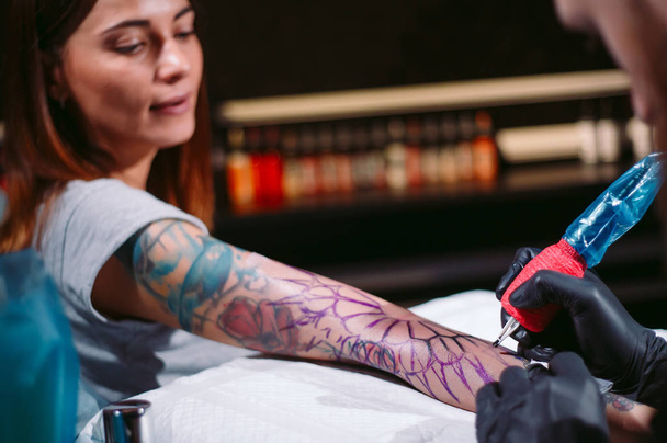 Professional tattoo artist makes a tattoo on a young girls hand. - Foto, immagini