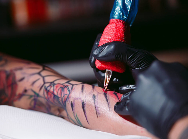 Professional tattoo artist makes a tattoo on a young girls hand. - Fotografie, Obrázek