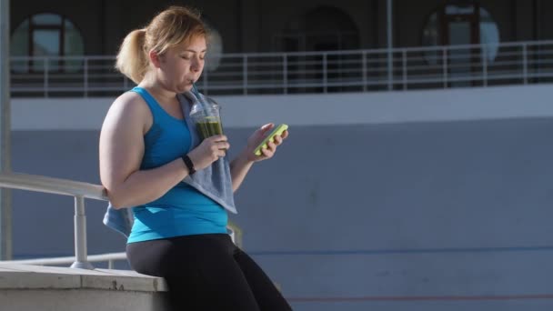 Υπέρβαρη γυναίκα δρομέας πίνοντας πράσινο χυμό - Πλάνα, βίντεο