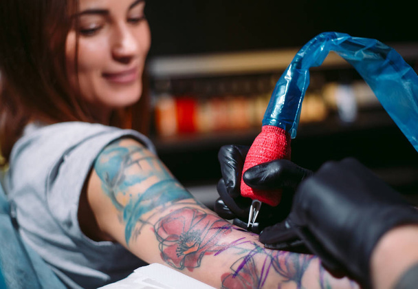 Professional tattoo artist makes a tattoo on a young girls hand. - Photo, image