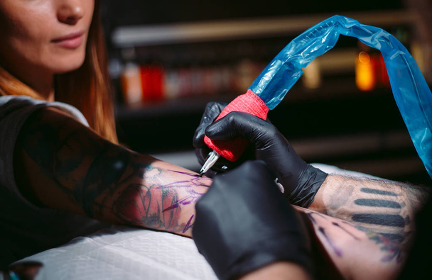 Professional tattoo artist makes a tattoo on a young girls hand. - Foto, Imagen