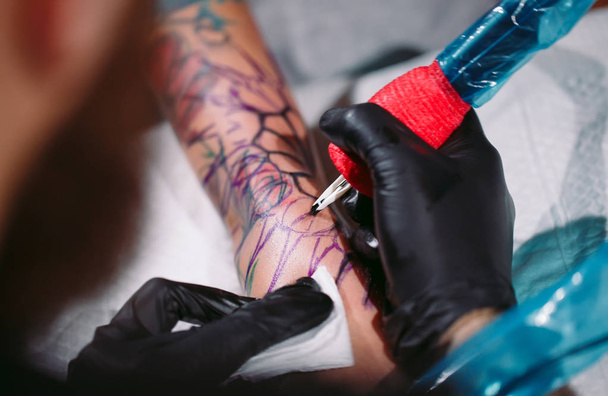 Professional tattoo artist makes a tattoo on a young girls hand. - Foto, Bild