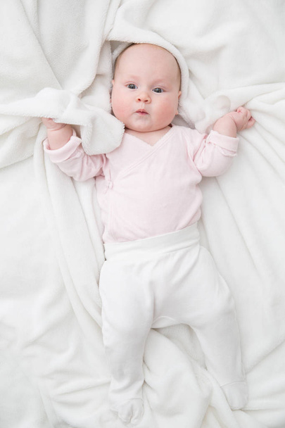 baby girl is lying on white blanket - 写真・画像