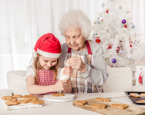 Grandmother teach granddaughter decorate cookies - Foto, Bild