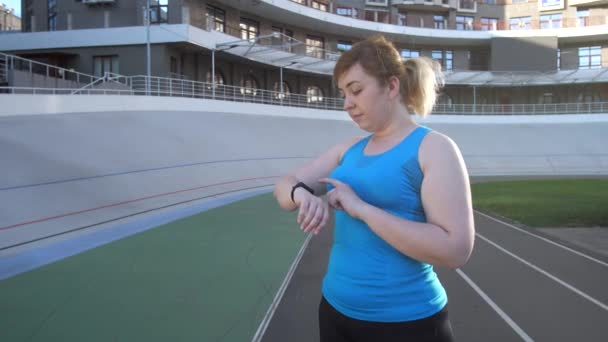 Woman runnner choosing options on fitness bracelet - Video, Çekim