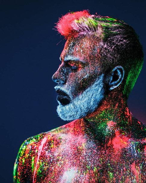 Concept. Portrait of a bearded man. The man is painted in ultraviolet powder. - Fotó, kép