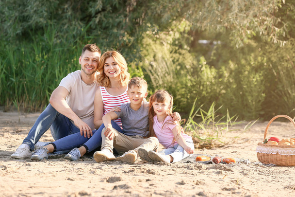 川の近くの夏のピクニックで幸せな家族 - 写真・画像