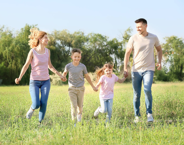 Ευτυχισμένη οικογένεια τρέχει στο πάρκο την ημέρα του καλοκαιριού - Φωτογραφία, εικόνα