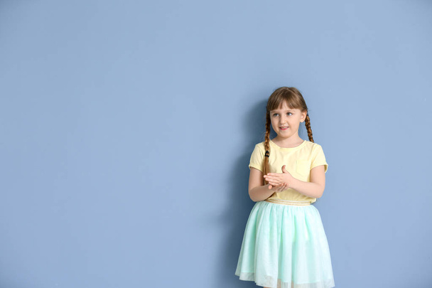 Cute deaf mute girl using sign language on color background - Photo, Image