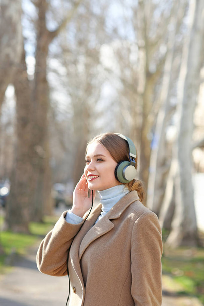 Mooie jonge vrouw, luisteren naar muziek in park - Foto, afbeelding