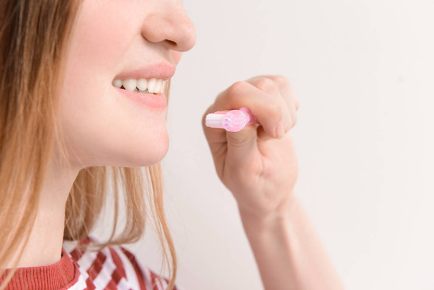 Nainen, jolla on hammasharja kevyellä taustalla, lähikuva. Hammashygienian käsite
 - Valokuva, kuva