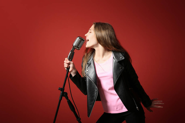 Έφηβο κορίτσι με μικρόφωνο τραγουδώντας με φόντο το χρώμα - Φωτογραφία, εικόνα