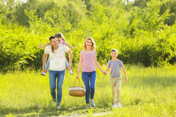 Ευτυχισμένη οικογένεια με τα πόδια στο πάρκο την καλοκαιρινή μέρα - Φωτογραφία, εικόνα