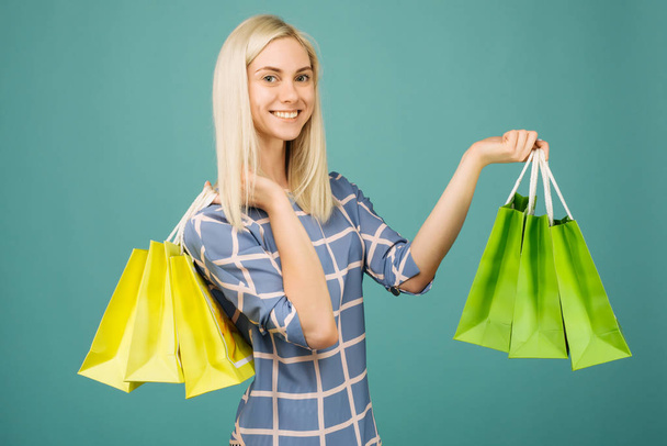 Chica feliz en una blusa a cuadros sostiene bolsas de compras
 - Foto, imagen