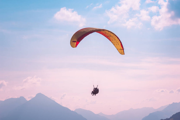 Paralotniarstwo w tandemie w Interlaken, Szwajcaria. Sfotografowany w różowe światło zachodu słońca. Sylwetki paralotniarki i Alpy Szwajcarskie. Styl życia przygody. Sporty ekstremalne. Aktywność adrenalina - Zdjęcie, obraz