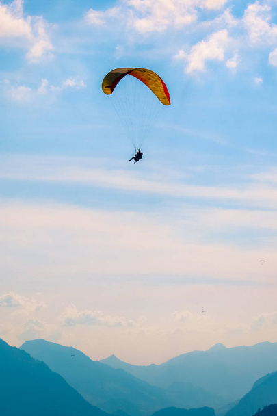 Tandem paragliding over de Zwitserse Alpen in Sunset Light. Gefotografeerd in Interlaken, Zwitserland. Silhouetten van Zwitserse Alpen en paragliders. Avontuurlijke sporten, extreem. Adrenaline-activiteiten. Conceptuele - Foto, afbeelding