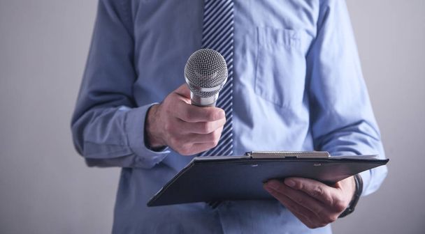 Caucasian businessman standing in office holding microphone.   - Valokuva, kuva