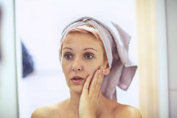 Il concetto di cura della pelle. donna è preoccupata per le rughe sul suo viso
 - Foto, immagini