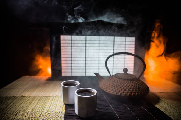 Concetto tè. Cultura cerimonia del tè giapponese bevanda orientale. Teiera e tazze sul tavolo con foglie di bambù al tramonto
 - Foto, immagini