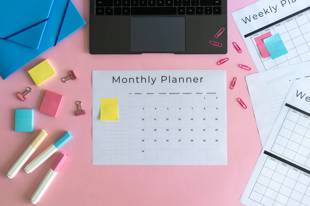 Laptop, briefpapier en planner op roze pastel achtergrond - Foto, afbeelding