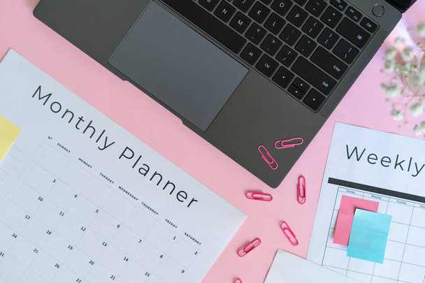 Ноутбук, канцелярські товари та планувальник на рожевому пастельному фоні
 - Фото, зображення
