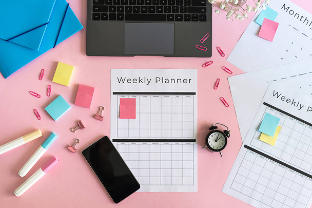 Smartphone, ordinateur portable, papeterie et planificateur sur fond rose pastel
 - Photo, image