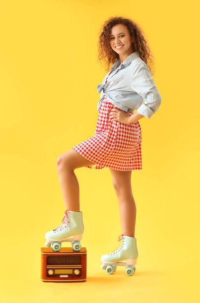 Kaunis nuori nainen rullaluistimilla ja retroradiovastaanottimella väritaustaa vasten
 - Valokuva, kuva