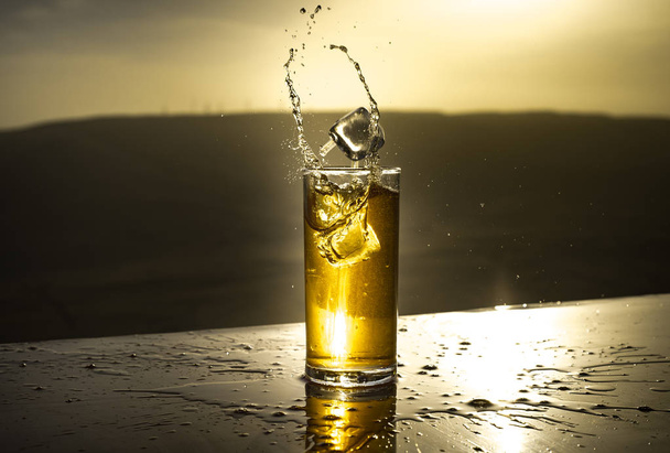 Hűsítő nyári ital koncepció. Koktél szemüveg fröccsenő naplemente. Zárjon be egy nedves pohár hideg italt a teraszon. - Fotó, kép