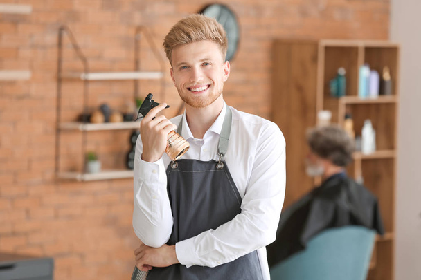 Young male hairdresser in beauty salon - Fotó, kép