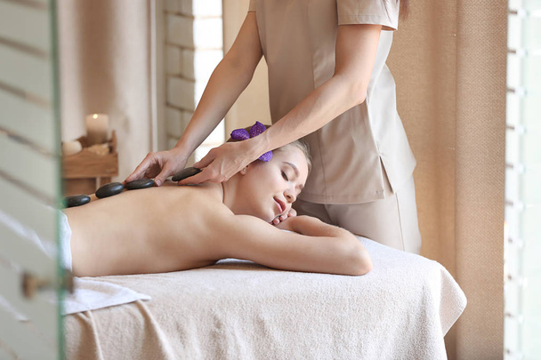 Bella giovane donna sottoposta a trattamento con pietre da massaggio nel salone spa
 - Foto, immagini
