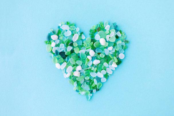 sea glass pieces in the shape of a heart on blue background - Fotó, kép