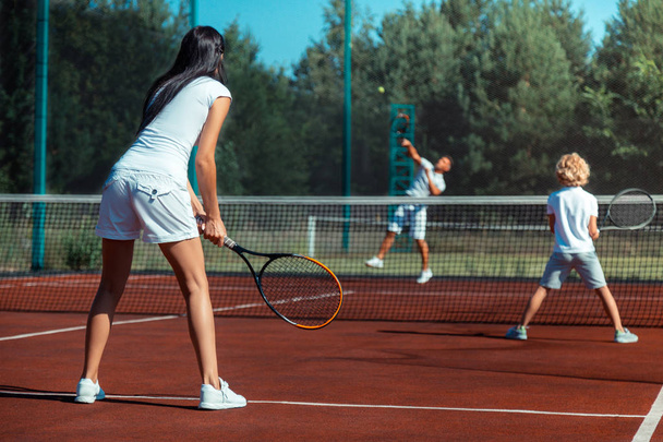 Dark-haired wife playing tennis with husband and son - Photo, image