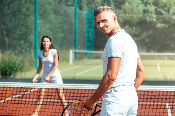 Handsome athletic man playing tennis with wife - Foto, afbeelding