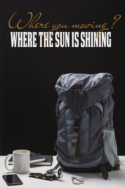 zaino, tazza, quaderni, smartphone e attrezzatura da trekking isolati su nero con dove si muove la domanda e dove il sole splende risposta
 - Foto, immagini