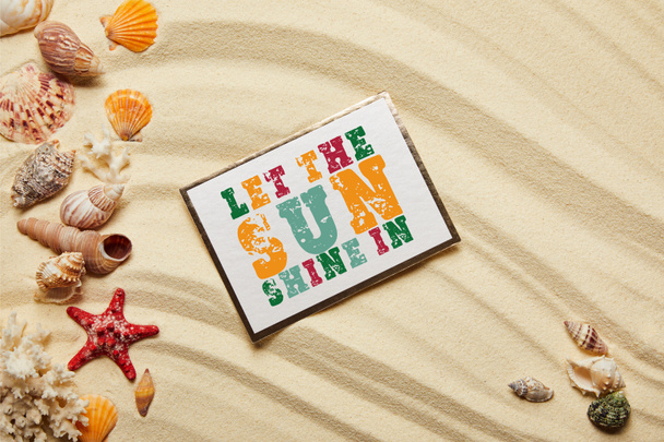 felülnézet kártya hagyja, hogy a nap ragyog betűkkel közelében tengeri kagylókból, vörös csillag és a korallok homokos tengerparton  - Fotó, kép