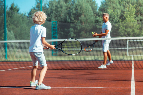 Father and son enjoying warm summer day playing tennis outside - Φωτογραφία, εικόνα