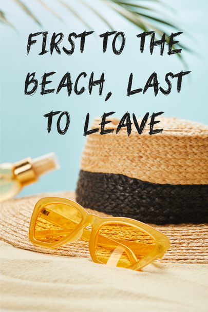 sunglasses near straw hat and bottle with suntan oil on sandy beach isolated on blue with first to the beach, last to leave illustration - Foto, imagen
