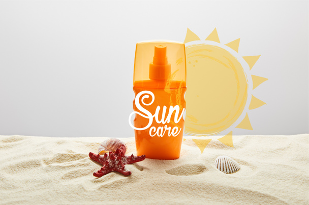 sunscreen in orange bottle on sand with starfish on grey background with sun care lettering - Photo, Image
