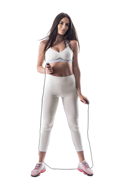 Γυναικείο αερόβια γυμναστή με αθλητικό σώμα που κρατά άλμα ή σκοινί. Ολόκληρο το σώμα απομονώνεται σε λευκό φόντο.  - Φωτογραφία, εικόνα