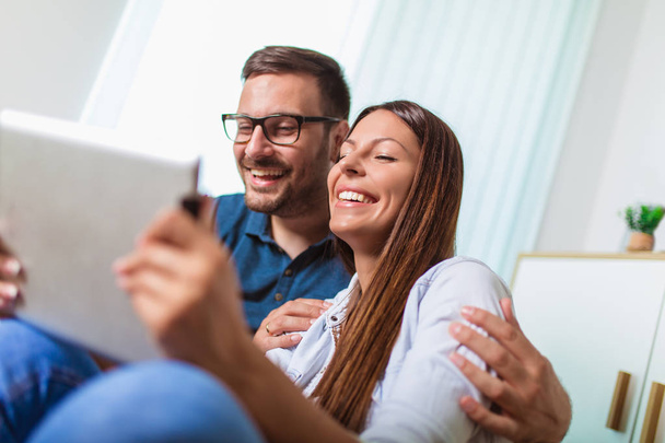 Genç çift li bir tablet te medya içeriği online izliyor - Fotoğraf, Görsel