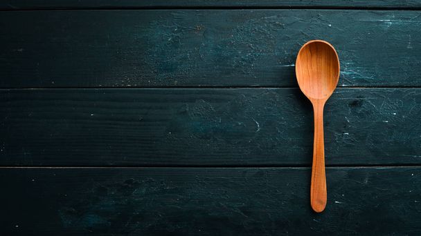 A wooden spoon on a black background. Top view. Free space for your text. - Photo, image