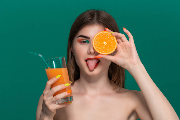 Closeup portrait of beautiful young woman with bright color make-up drinking orange juice - Фото, изображение