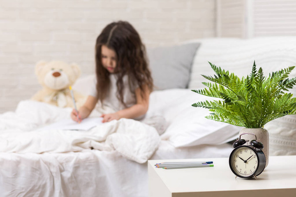 cute little girl drawing pictures while lying on bed - Valokuva, kuva