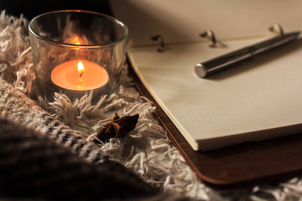 Hygge stijl. Warme deken, brandende kaarsen, boek voor notities. vintage stijl, stilleven. - Foto, afbeelding