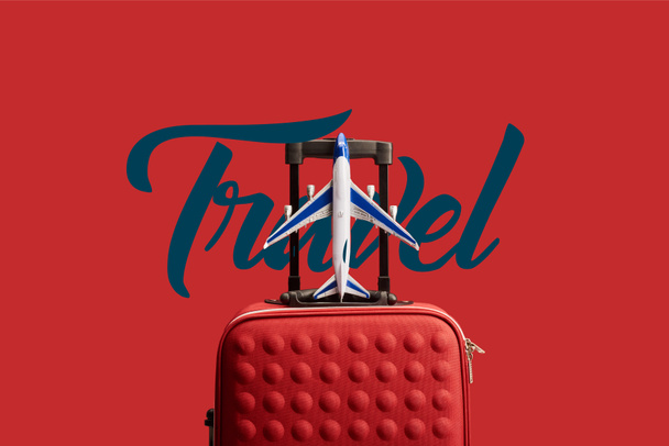 red colorful textured travel bag with plane model isolated on red with travel illustration - Foto, Imagem