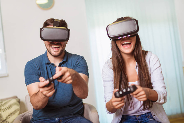Młoda szczęśliwa para grając w gry wideo wirtualnej rzeczywistości okulary.  - Zdjęcie, obraz