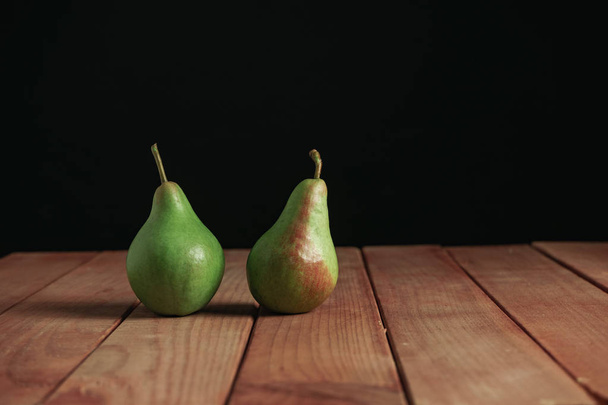 Fresh green pears on a red wooden table, beautiful black background. - Fotoğraf, Görsel